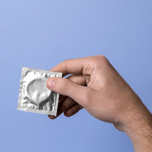 Man holding condom to illustrate section on free condom distribution.