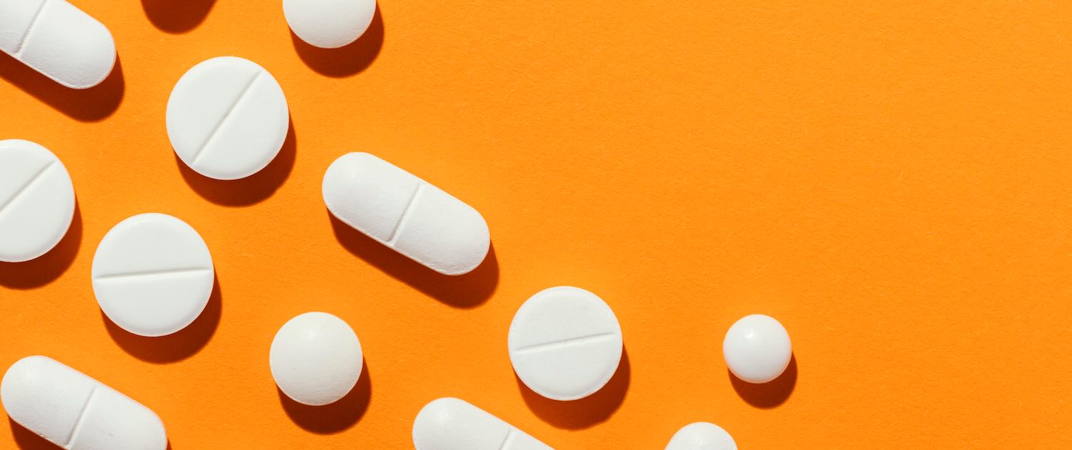 Illustration of white pills against an orange background.